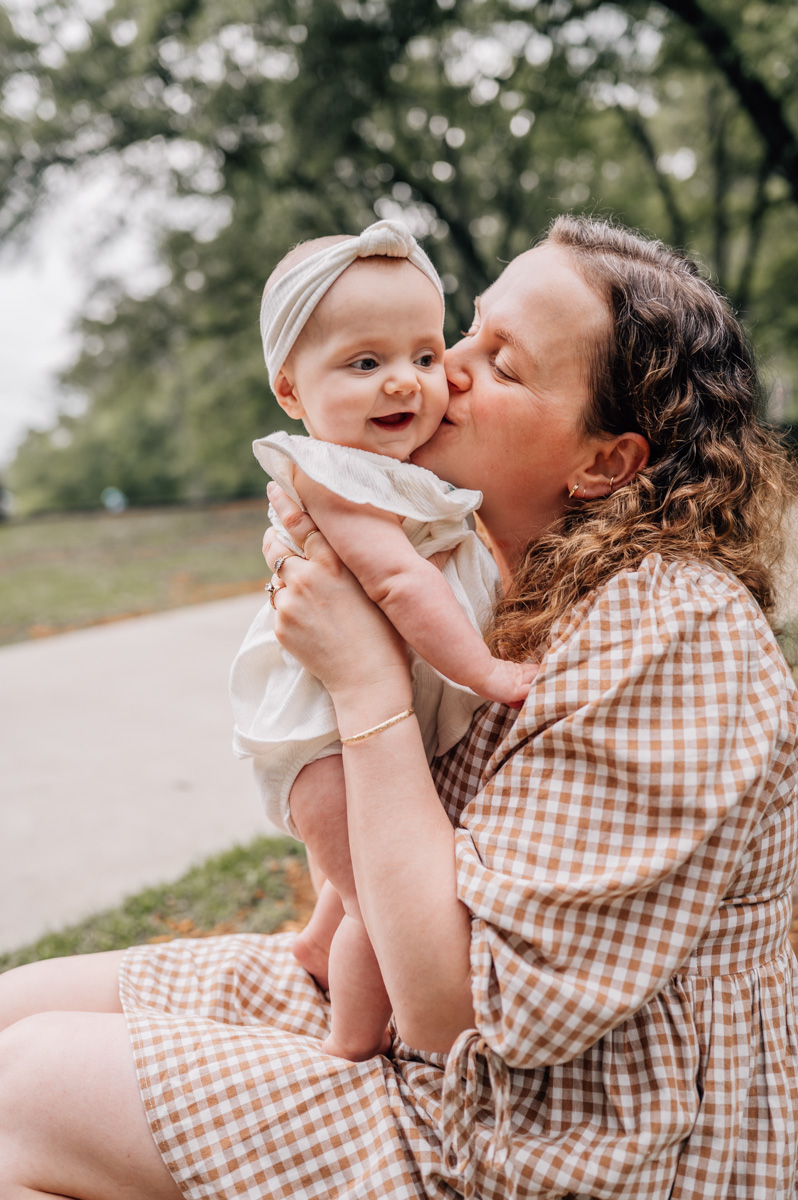 Mom kissing her baby girl during outdoor family session with Oh mama photography: Columbia SC Family Photographer