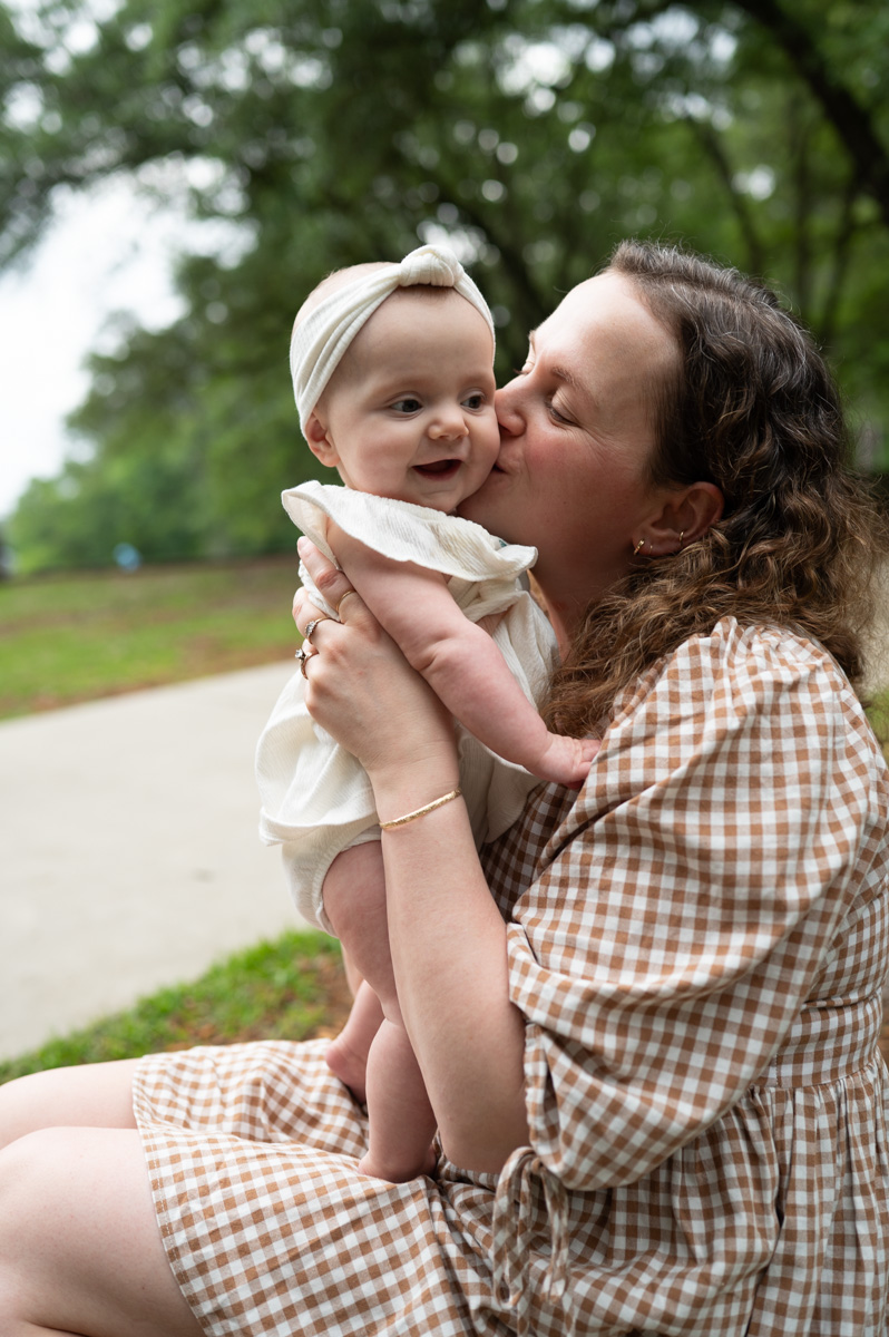 Mom kissing her baby girl during outdoor family session with Oh mama photography: Columbia SC Family Photographer