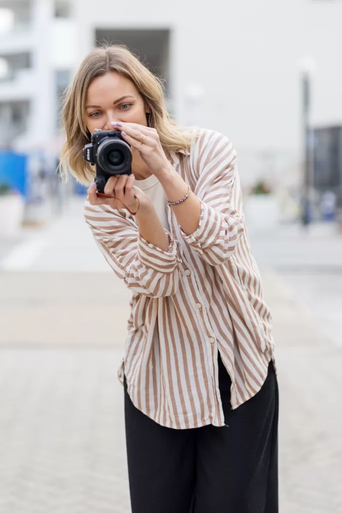 Pola Seeley - newborn photographer holding a camera in front of her and taking a picture of a newborn baby.