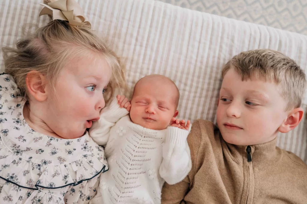 4 year old and 6 year old looking at their newborn baby sister.