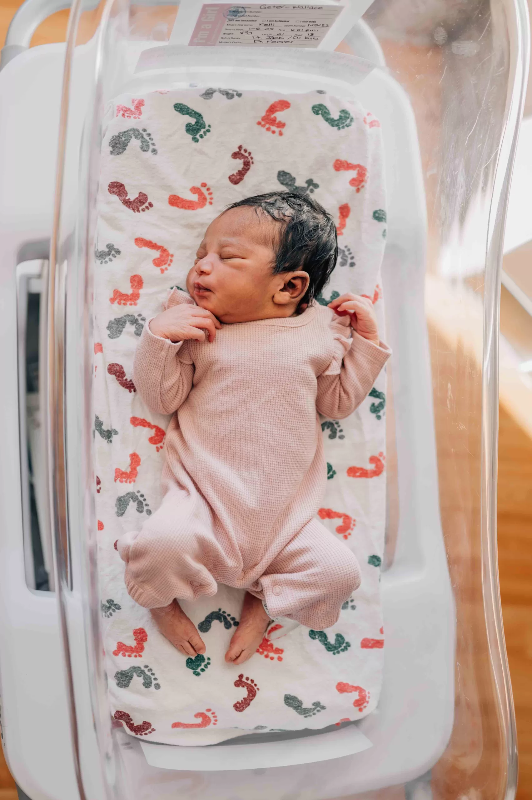 A newborn abby girl sleeps in a hospital crib in a pink onesie thanks to childbirth classes in Columbia, SC