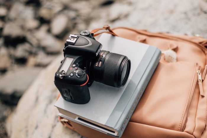 Nikon D750 for Newborn Photographer - oh mama photogaphy. A book by Jodi Picoult laying on the Ayla and Co backpack on the rocks.